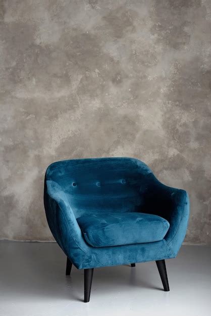 Sillón art déco de terciopelo azul clásico con patas de madera contra