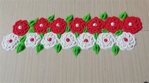 red and white crocheted flowers with green leaves on the bottom, sitting on a wooden surface