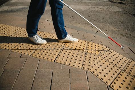 Joven ciego con bastón blanco cruzando la calle en la ciudad Foto Premium