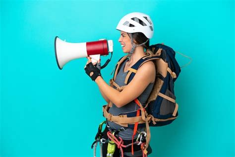 Jovem alpinista italiana isolada em fundo azul gritando através de um