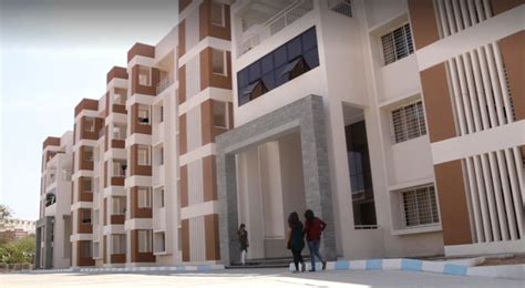 Two People Walking In Front Of An Apartment Building