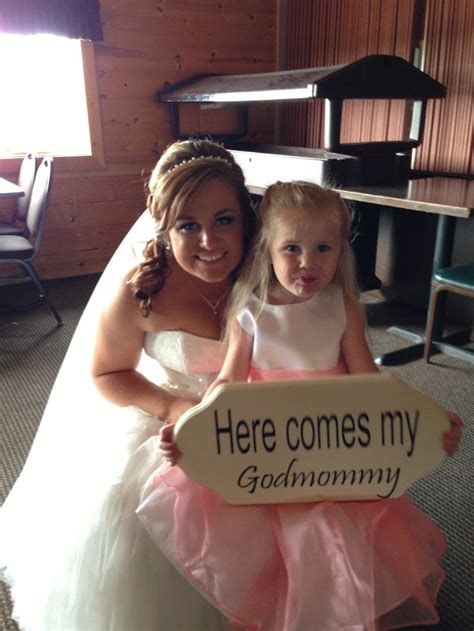 A Bride And Her Flower Girl Pose For A Photo In Front Of A Sign That