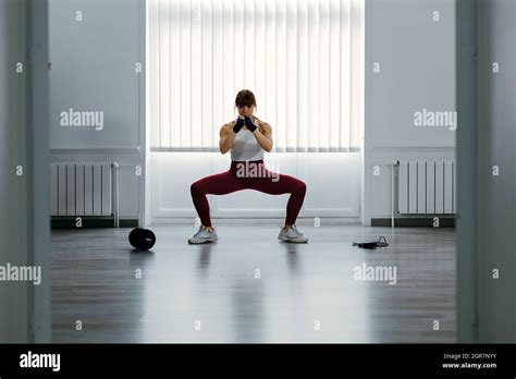 Ajustar A La Mujer Haciendo Sentadilla Bajo Una Gran Ventana Deportes