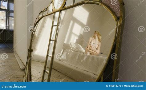 A Lovely Blonde Girl In A Nightie On A White Bed Bending Her Legs