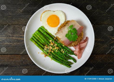 Asparagus In Oyster Sauce With Fried Ricebacon And Egg In White Dish On Wooden Table Background