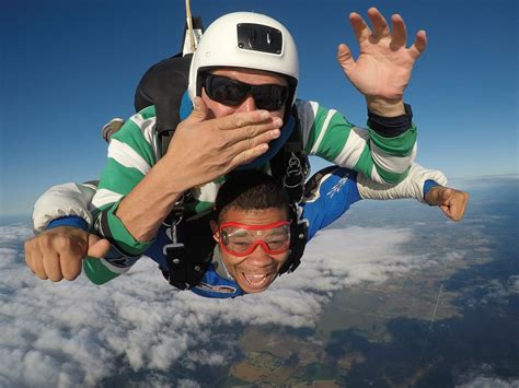 Tandem Skydiver Giving Thumbs Up And Instructor Blowing A Kiss At