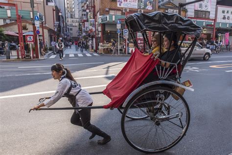 Two People Touring On A Rickshaw Jinrikisha Pulling By A Woman In