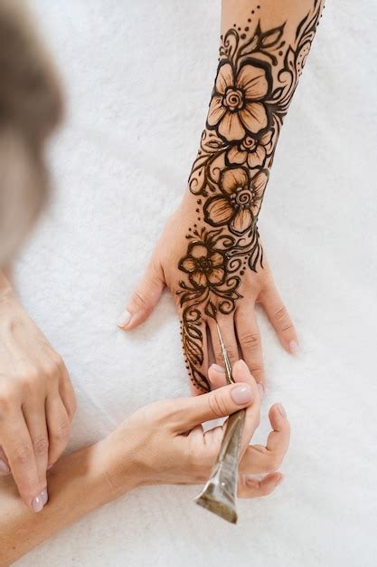 Premium Photo Artist Applying Floral Henna Tattoo On Women Hands