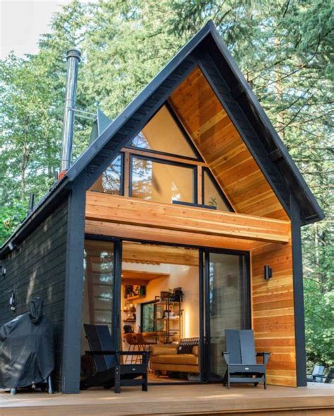 A Small Cabin In The Woods With Wood Sidings And Glass Doors On The Front