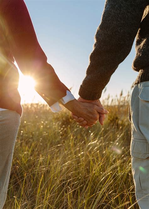 Senior Couple Love Holding Hands Outdoors Backlit At Sunset By