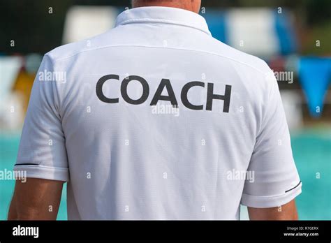 Back View Of Swimming Coaches Wearing Coach Shirt Working Together At