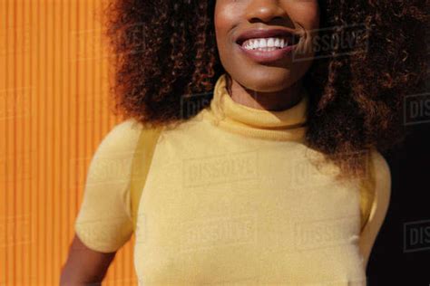 Portrait Of A Curly Haired Black Woman Looking At Camera In Front Of A