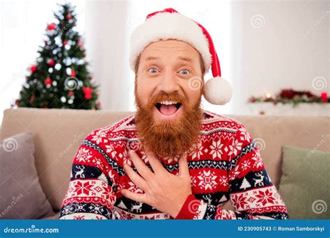 Photo Of Good Mood Smiling Amazed Male In Santa Hat Hold Hand Chest