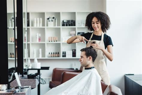 Female Black Barber Cutting Hair Of Young Man Client Stock Photo