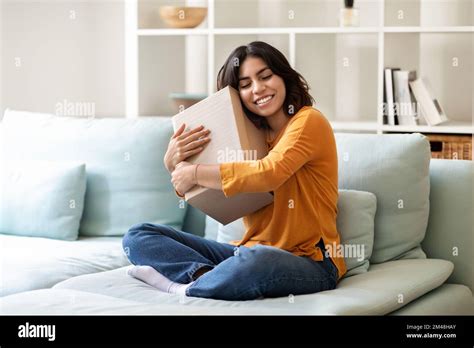 Femme arabe embrassant une grande boîte en carton tout en étant assise