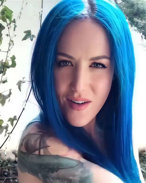 A Woman With Blue Hair And Tattoos Posing For A Photo In Front Of Some