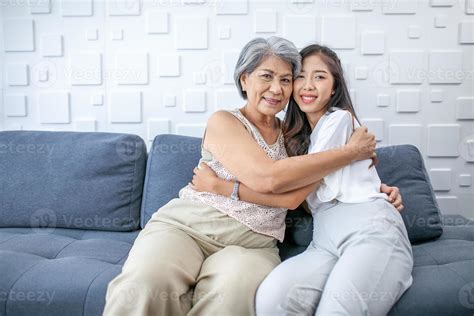 Asian Grandma And Granddaughter Hugged With Happy Mood On The Sofa In