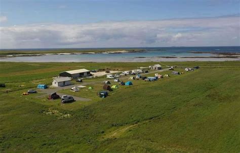 An Aerial View Of A Camp Site Near The Ocean With Cars Parked In Front