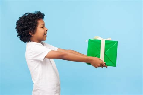 Tome este presente vista lateral de un niño alegre generoso y