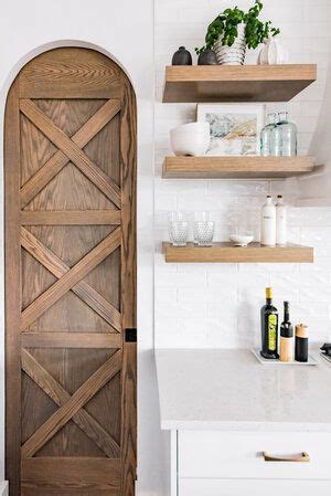 A Kitchen With Open Shelving And Wooden Doors