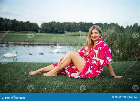 Beautiful Smiling Blonde Woman Lying On The Grass Outdoors She Is