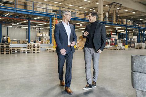 Happy Mature Businessman Discussing With Colleague In Warehouse Stock Photo
