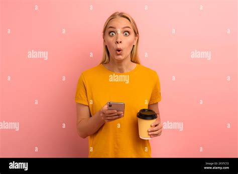 Blonde Cute Girl Types A Message With Her Smartphone Happy And Surprised Expression Face Pink