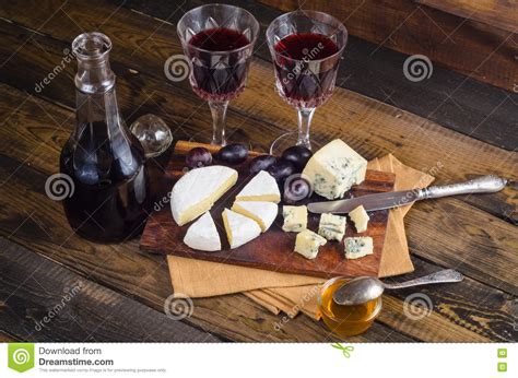 Placa De Queso Con La Uva Y El Vino En La Madera Foto De Archivo