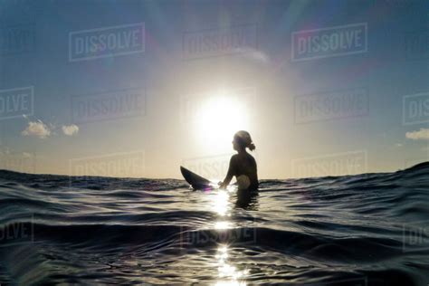 Silhouette Of Surfer Sitting On Surfboard In Ocean Stock Photo Dissolve