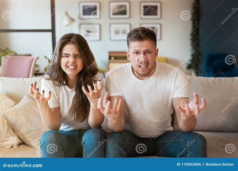 Young Couple Man And Woman Sitting On The Sofa Both Looking Mad