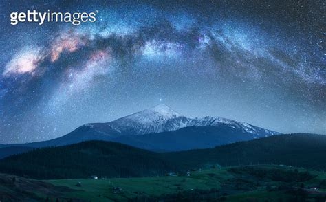 Arched Milky Way Over The Beautiful Mountains With Snow Covered Peak At