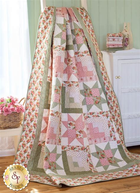 A Pink And Green Quilt Hanging From The Side Of A Bed