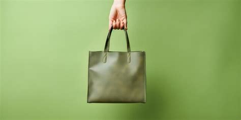 Premium Ai Image Hand Holding A Leather Handbag On A Green Background