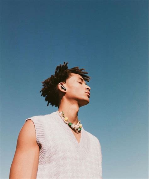 A Man With Dreadlocks Standing In Front Of A Blue Sky Wearing A White