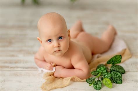 Un niño pequeño un niño yace desnudo sobre su estómago y mira a la