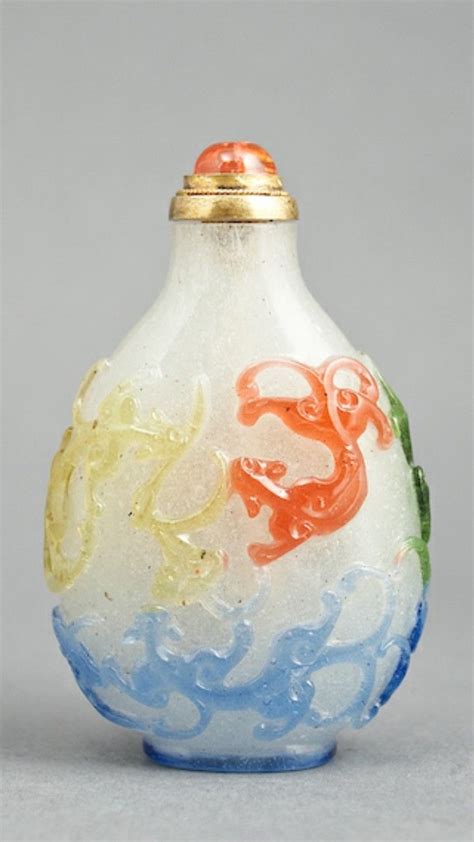 A Small Glass Vase With Colorful Designs On The Top And Bottom Sitting