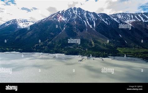 An Aerial View Of A Snowy Mountain Range Covered With Clouds Against A