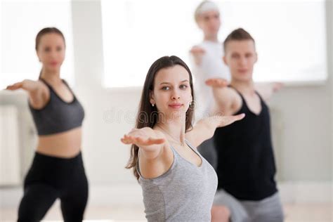 Group Of Sporty People Practicing Yoga Warrior Two Pose Stock Image