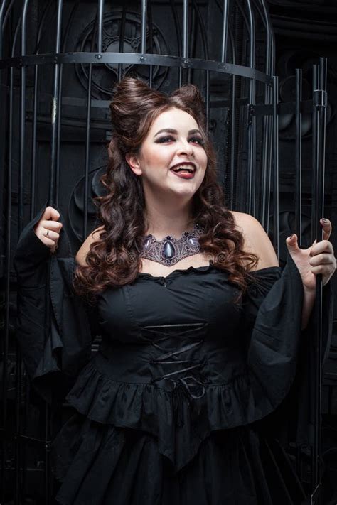 De Mooie Mollige Vrouw Bevindt Zich Door De Zwarte Kooi Stock Afbeelding Image Of Brunette