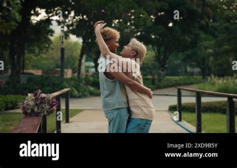 Affectionate Gay Partners Kiss And Hug Standing On Bridge In Green