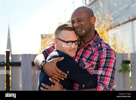 Smiling Gay Men Embracing Against Fence Stock Photo Alamy
