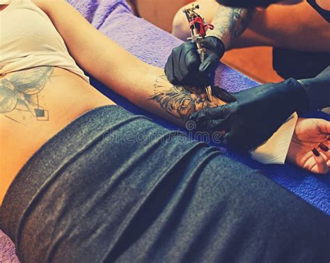 L Artiste Masculin De Tatouage Fait Un Tatouage Sur Une Jambe Femelle