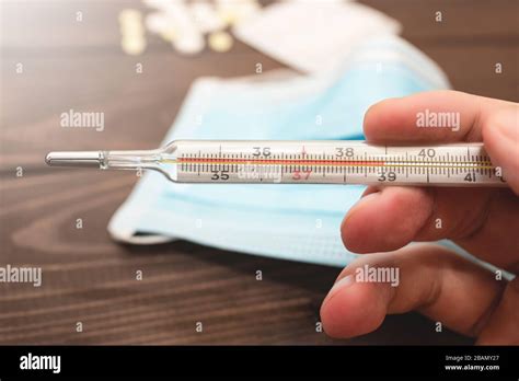 A Medical Clinical Mercury Thermometer In Persons Hand Showing The