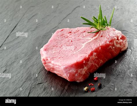 Portion Of Lean Raw Beef Steak With A Sprig Of Fresh Rosemary And