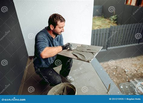 Tiler Placing Ceramic Wall Tile In Position Over Adhesive With Lash