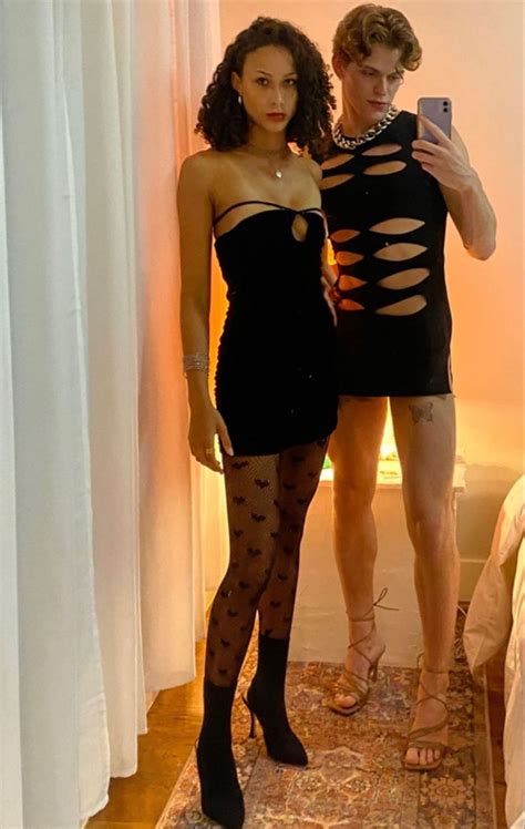 Two People Standing In Front Of A Mirror Taking A Selfie With Their