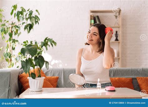 Woman Sitting On Couch Gives Herself Head Massage With Scalp Massager