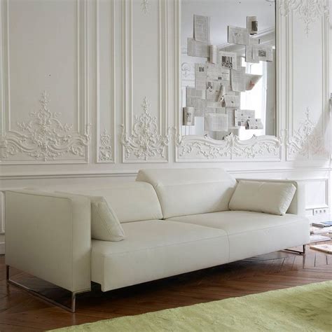 A White Couch Sitting In Front Of A Large Mirror