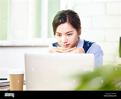 Young Asian Businesswoman Looking At Laptop Computer Thinking In Office