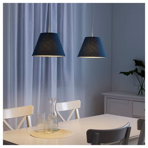 two lamps hanging over a dining room table with chairs and vases on the ...